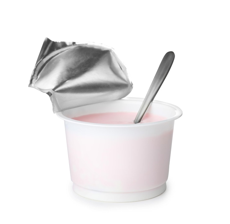 Photo plastic cup with creamy yogurt and spoon on white background