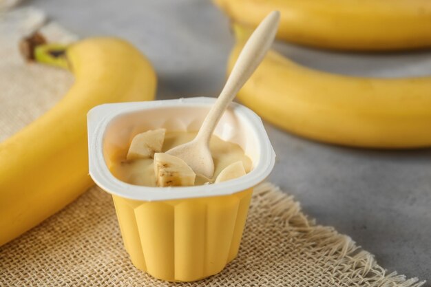 Plastic cup with yummy banana yogurt on table