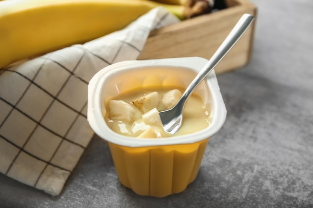 Plastic cup with yummy banana yogurt on table