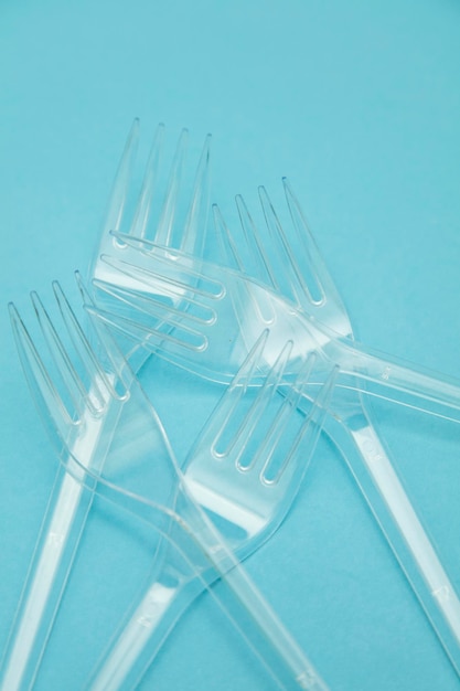 Plastic cutlery forks arranged on a blue background Plastic waste problem