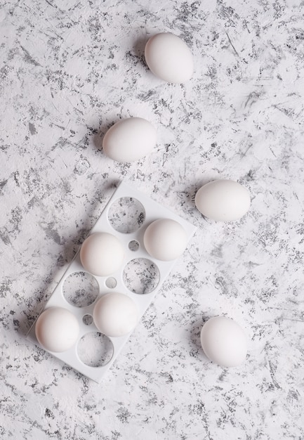 Plastic dienblad met witte eieren op een witte concrete achtergrond