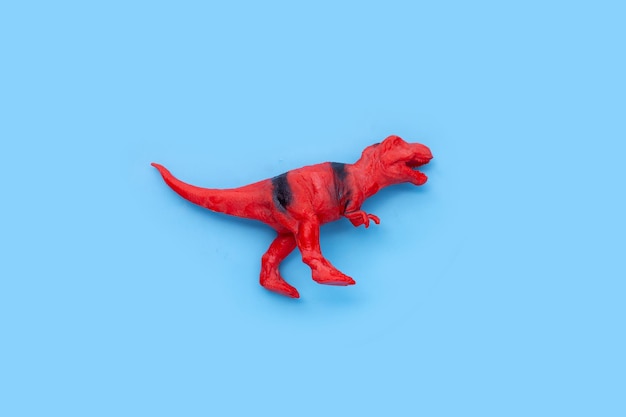 Plastic dinosaur toy on blue background Top view