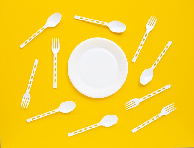 Plastic dish, spoon and fork on yellow