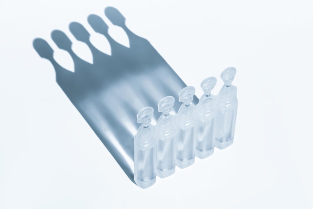 Plastic farmaceutische ampullen met fysiologische vloeistof Natriumchloride of druppels Geneesmiddel op een lichte achtergrond