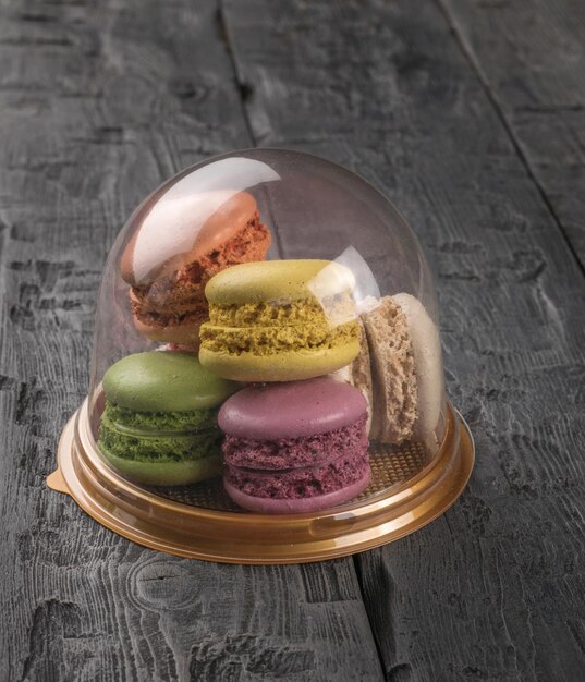 Plastic flask with colorful macaroon cookies on a wooden table