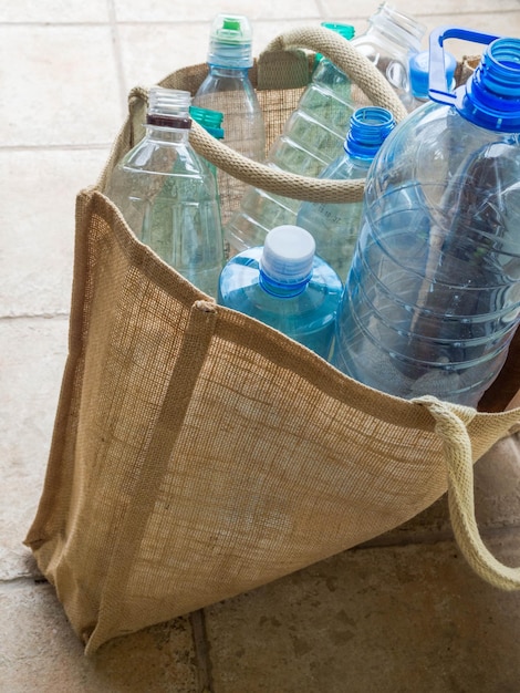 Plastic fles in jutezak Herbruikbare items voor dagelijks gebruik, alternatief voor wegwerp Ecologische levensstijl en zero waste-concept