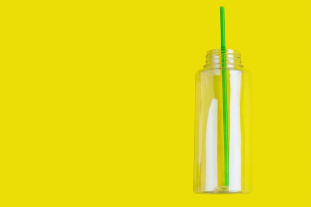 Plastic fles met een cocktailbuis op een gele achtergrond