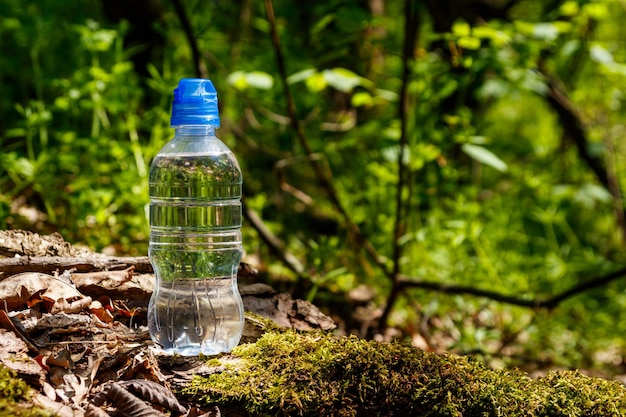 Plastic fles met vers drinkwater op groene bosachtergrond