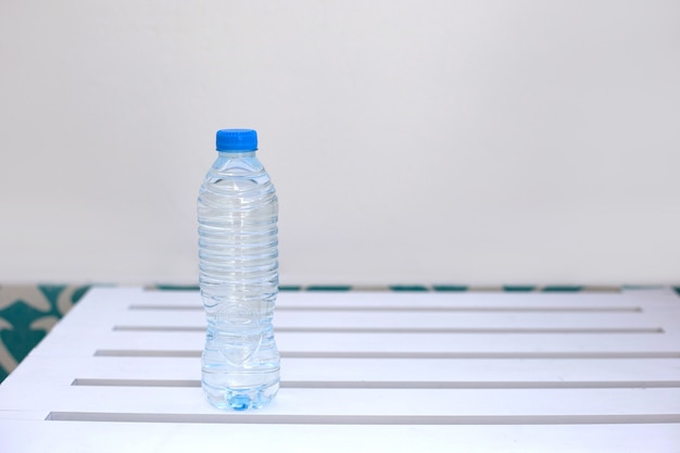 Plastic fles met water staat op witte houten tafel tegen witte muur achtergrond