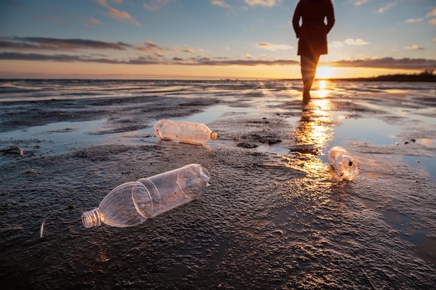 Plastic flessen aan land gegooid en de man op de achtergrond