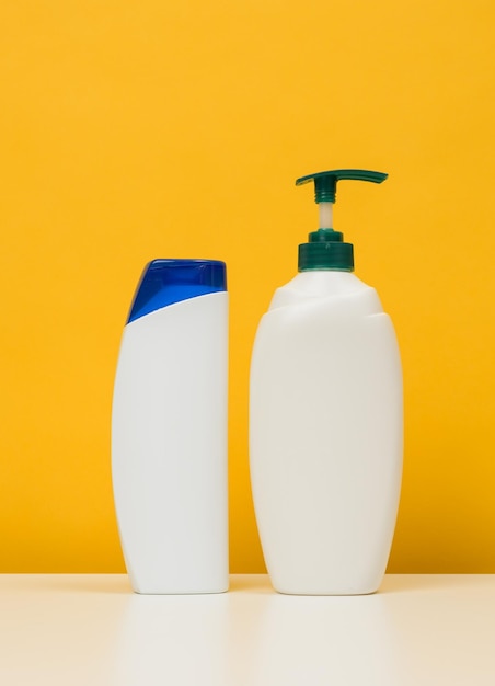 Plastic flessen met een pomp voor shampoo douchegel op een witte tafel gele achtergrond