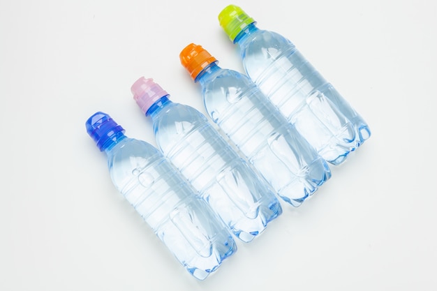 Plastic flessen water met doppen van verschillende kleur op de tafel
