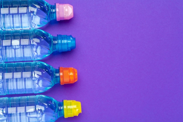 Foto plastic flessen water met doppen van verschillende kleur op de tafel