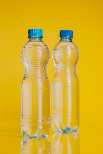 Plastic flessenhoogtepunt van drank op een heldere gele achtergrond