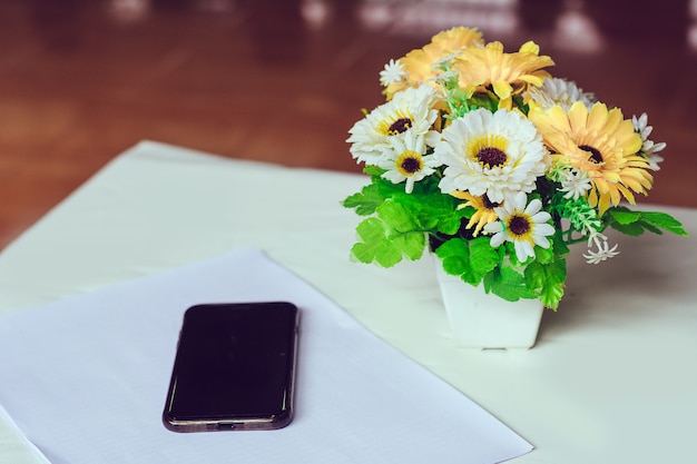 花瓶とスマートフォンとプラスチックの花。