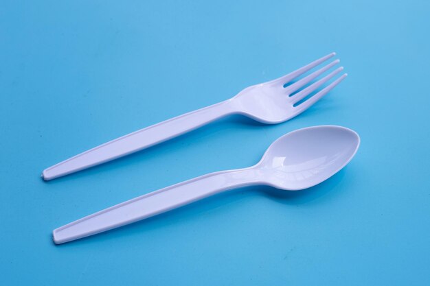 Plastic fork and spoon on blue background.