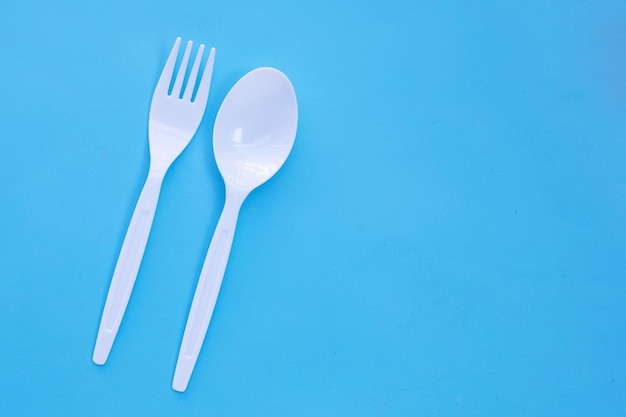 Plastic fork and spoon on blue background.