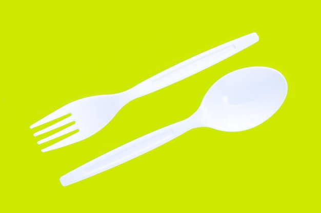 Plastic fork and spoon on green background.