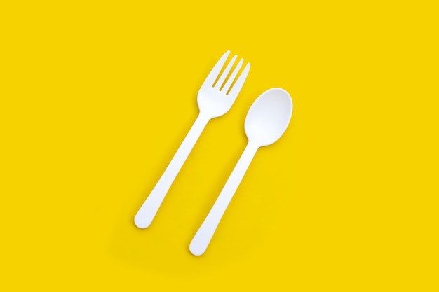 Plastic fork and spoon on yellow background