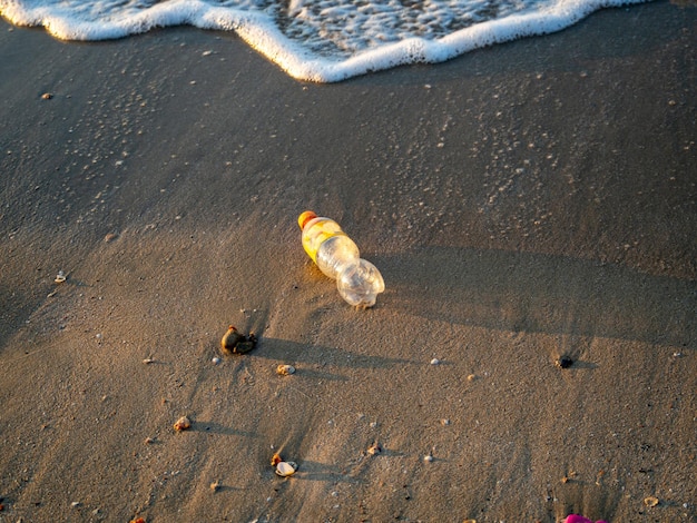 Plastic frisdrankflessen op het strand en de golven