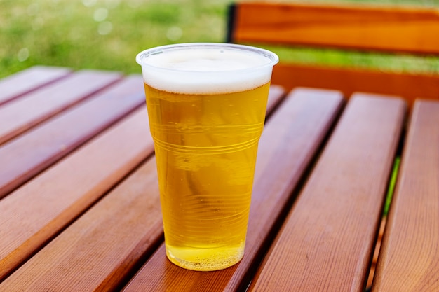 Plastic glas light bier, staande op een houten tafel, wegwerpglas. Koud bier.