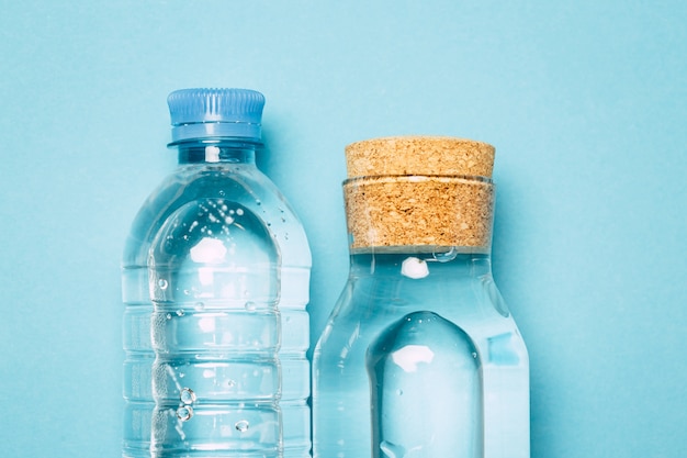 пластиковые и стеклянные бутылки для воды на синем фоне, альтернатива