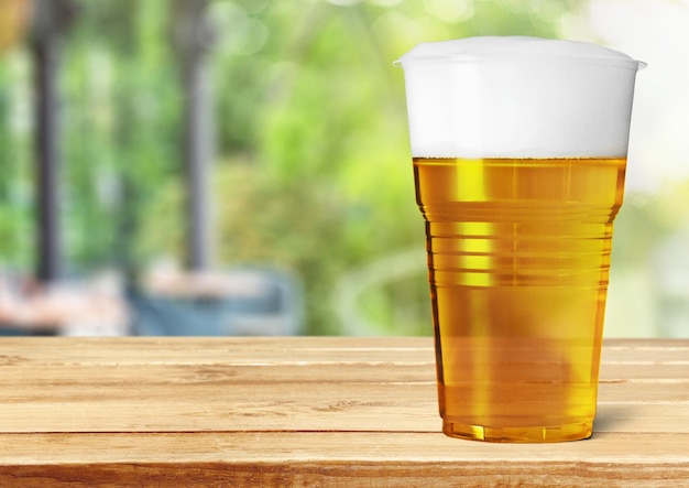 Plastic glass with beer on wooden background