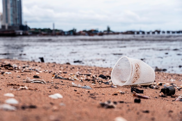 Пластиковые очки и мусор на песчаном пляже. Экологическая и пластиковая осведомленность. Концепция Всемирного дня окружающей среды. Спаси землю, спаси жизнь.