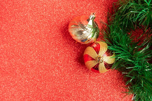 Plastic and glitter Christmas ornaments and Christmas garland on a red glitter surface. selective focus.