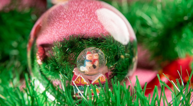 Photo plastic and glitter christmas ornaments viewed through a lensball on a pink glitter surface. selective focus.