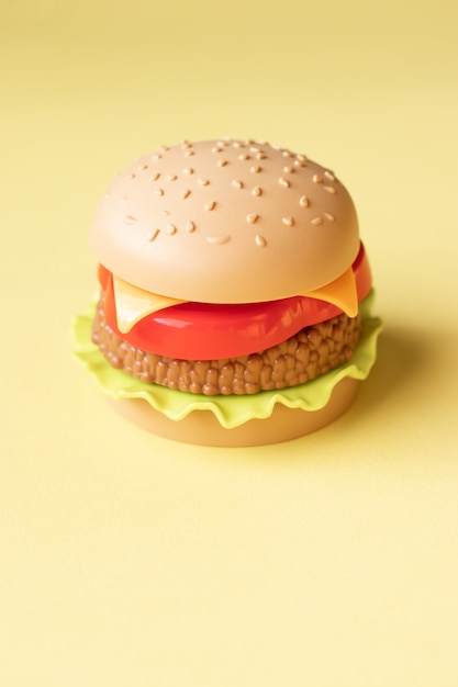 Plastic hamburger, salade, tomaat, op een gele backgroun