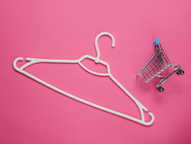 Plastic hanger and shopping trolley on pink paper
