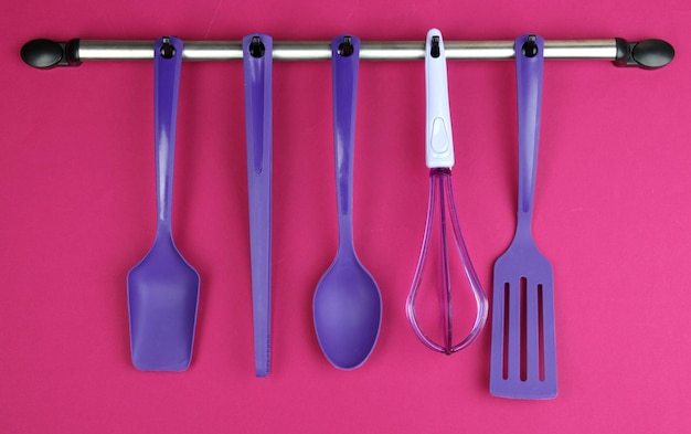 Foto utensili da cucina in plastica su ganci d'argento su sfondo rosso