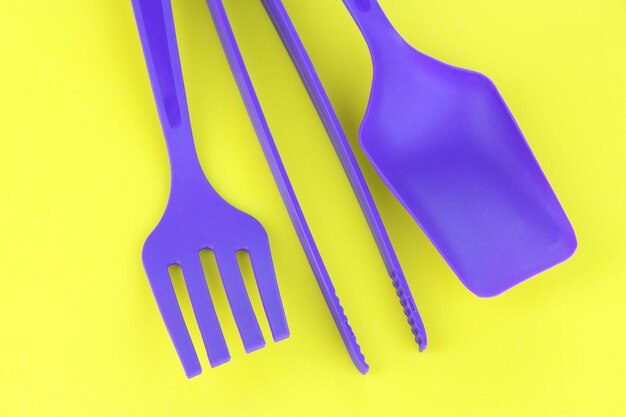 Photo plastic kitchen utensils on yellow background