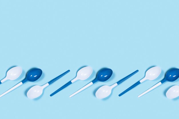 Plastic lepels op blauwe tafel.