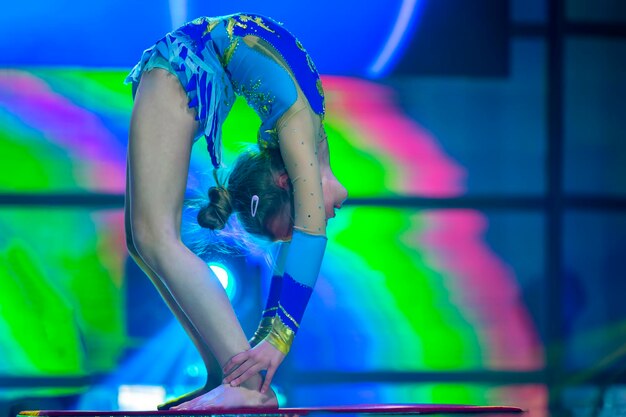 Plastic little girl gymnast a child with a flexible body performs on stage