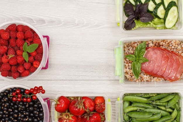 Plastic maaltijdbereidingscontainers met vers fruit, gekookte boekweitpap en plakjes vlees