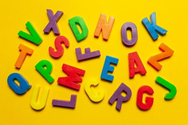 Plastic magnetische letters en cijfers geïsoleerd op gele bovenaanzicht Dyslexie en taalstoornissen