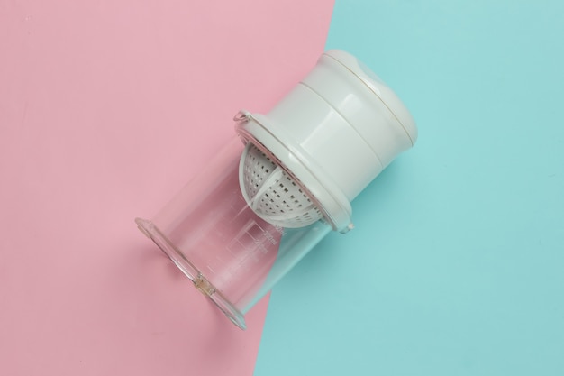 Plastic manual juicer on pink blue pastel background. Top view