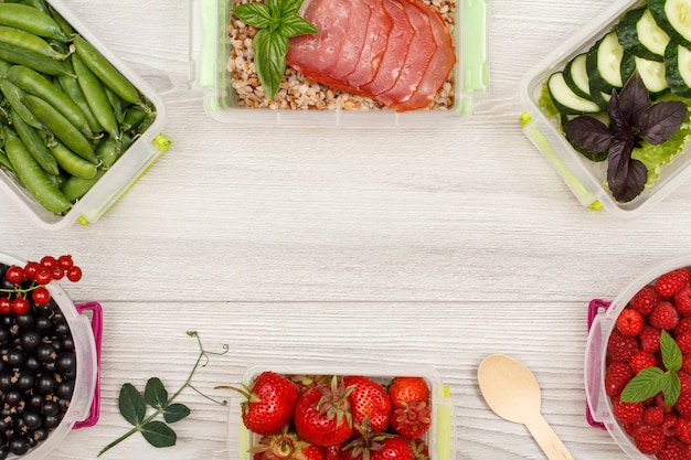 Plastic meal prep containers with black currant green peas strawberries buckwheat porridge