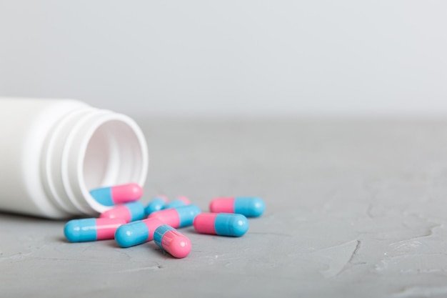 Plastic medicijnfles met capsules van pillen op gekleurde achtergrond Online apotheek Pijnstillergeneeskunde en antibioticum resistentieconcept Farmaceutische industrie