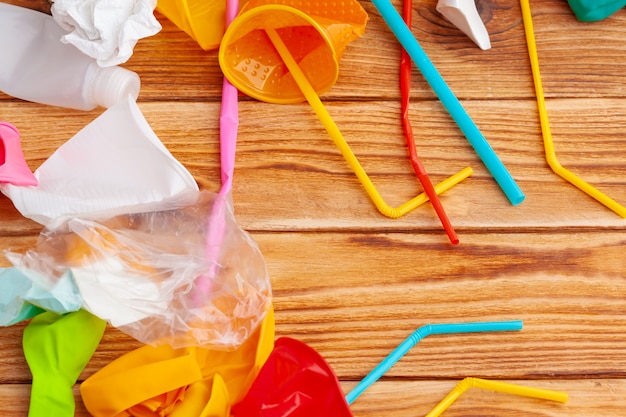 Gli oggetti di plastica, riciclano l'immondizia su una tavola di legno, vista superiore