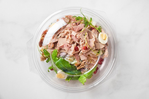 Photo plastic package with healthy baked ham salad for take away or food delivery on white background top view