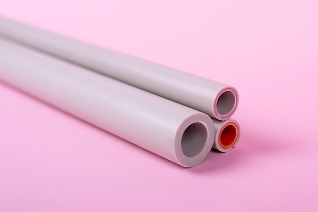 Пластиковые водопроводные трубы на розовом фоне канализационная установкаxa