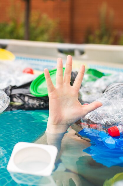 Plastic pollution and environmental problem, man's hand in plastic sea