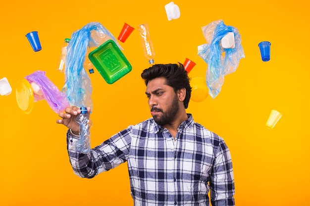 Plastic recycling problem, ecology and environmental disaster concept - surprised Indian man holding a plastic bag