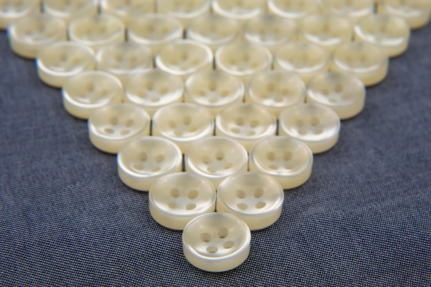 Plastic shiny buttons for clothes on a fabric background.\
fashion and clothing. factory industry.