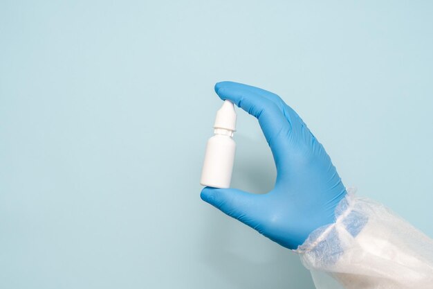 Plastic small bottle in doctors hand Eye ear or nose drops