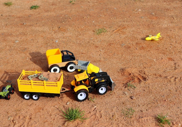 Plastic speelgoed auto's tractor en dump trucks op het zand in het park