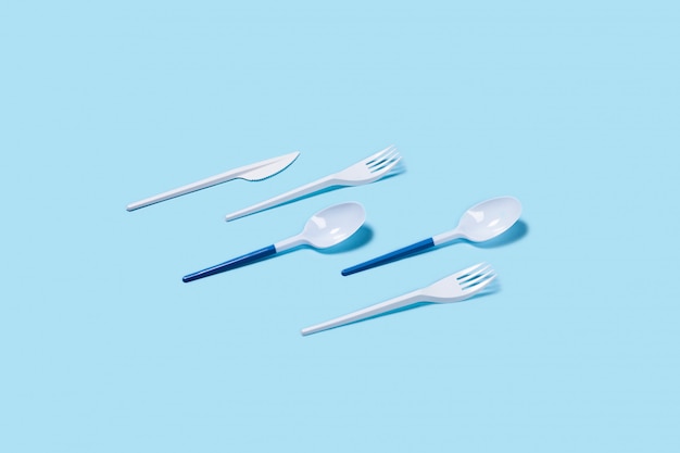 Plastic spoons and forks on blue background